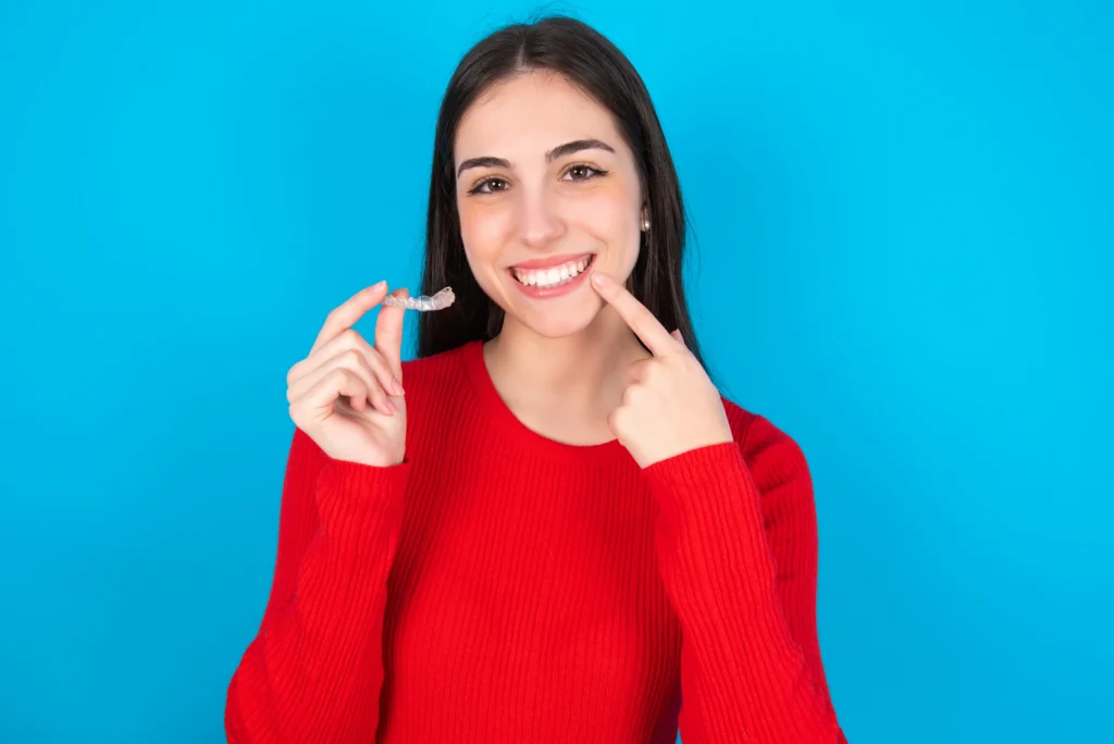 woman holding invisible aligner pointing her perfect straight teeth dental healthcare